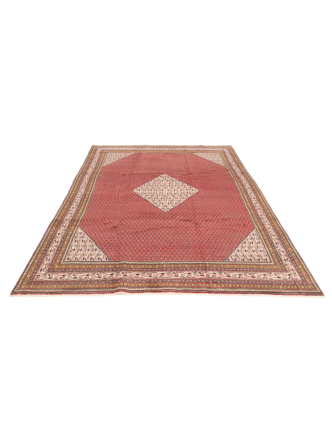A large, hand-knotted Sarough Mir rug with a vibrant red field and geometric motifs.