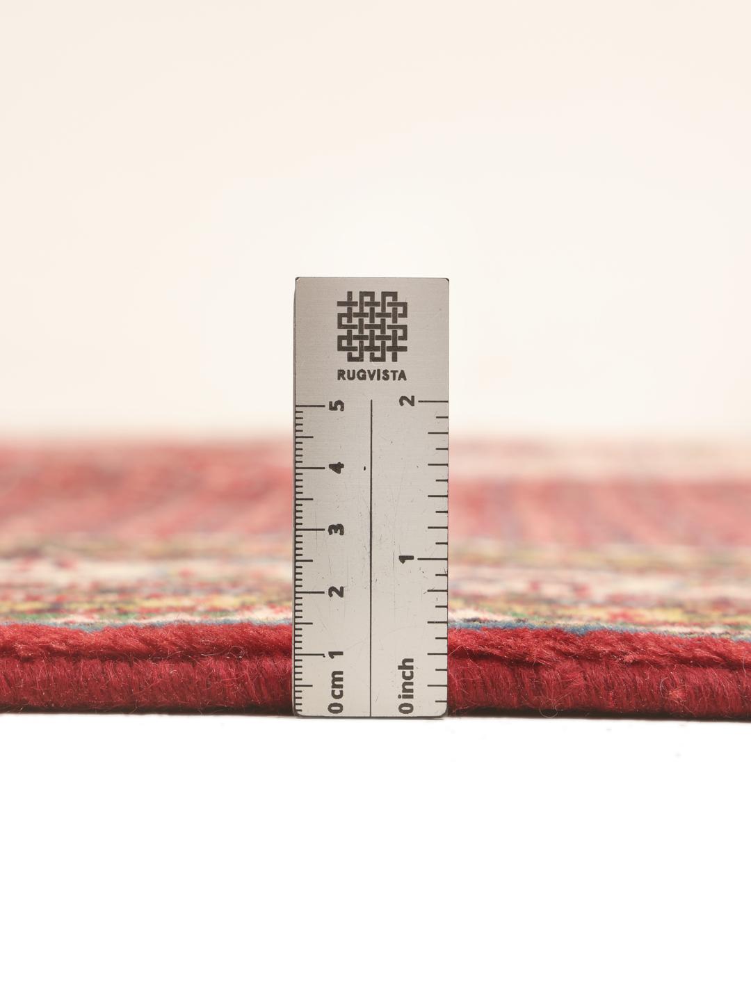 A large, hand-knotted Sarough Mir rug with a vibrant red field and geometric motifs.