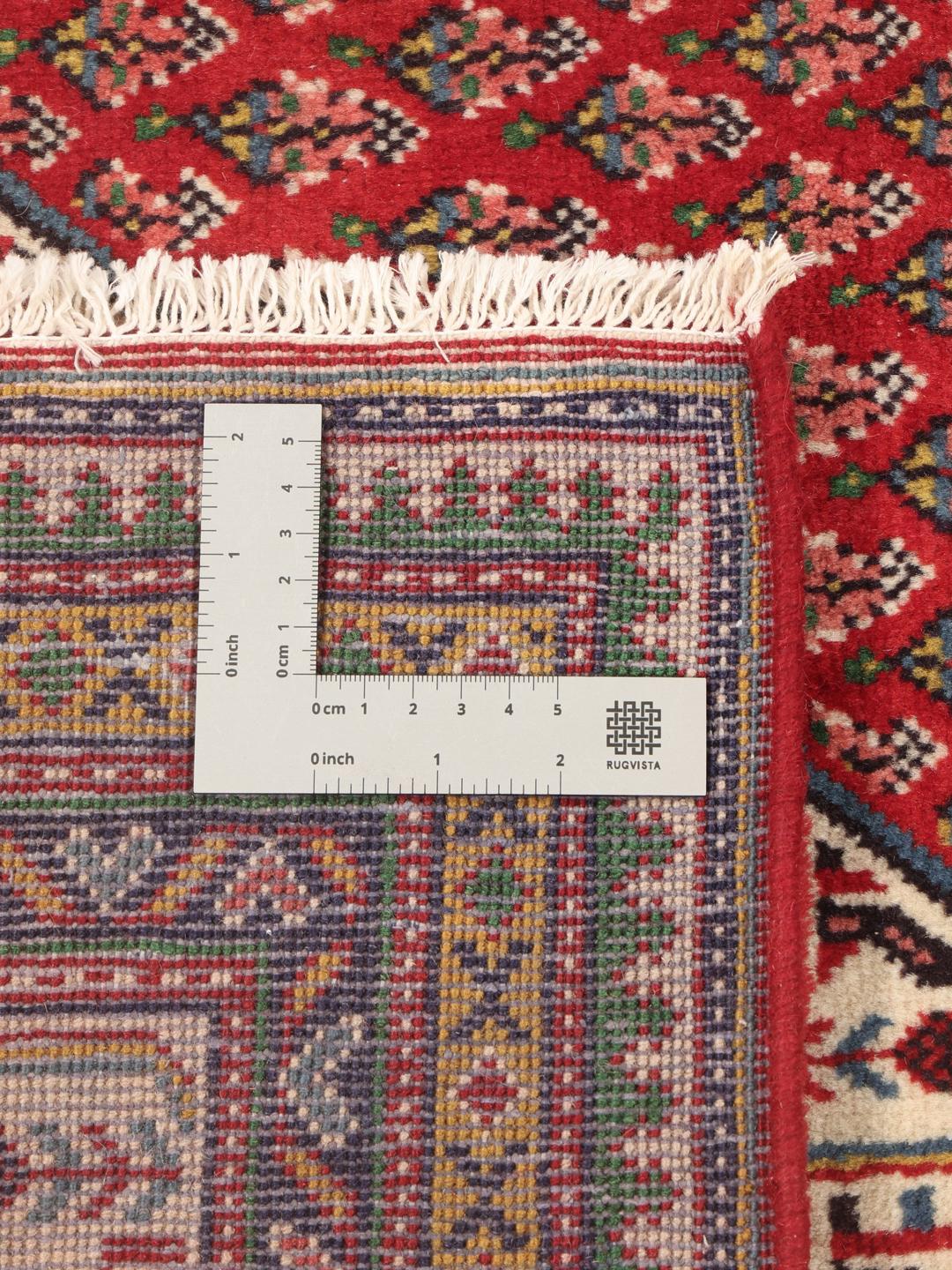 A large, hand-knotted Sarough Mir rug with a vibrant red field and geometric motifs.