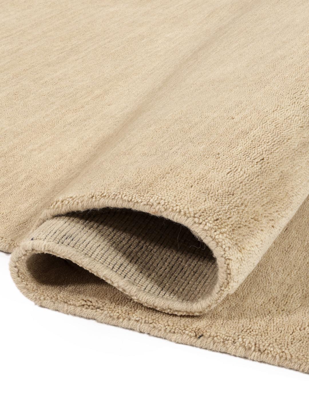 Een eenkleurig beige vloerkleed met verfijnde franjes