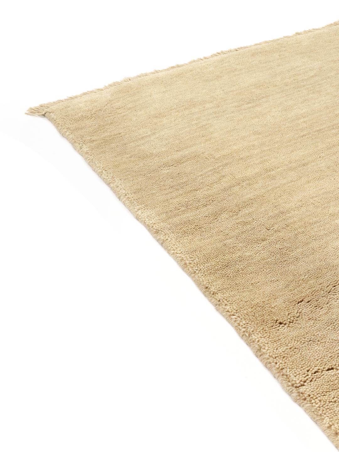 Een eenkleurig beige vloerkleed met verfijnde franjes