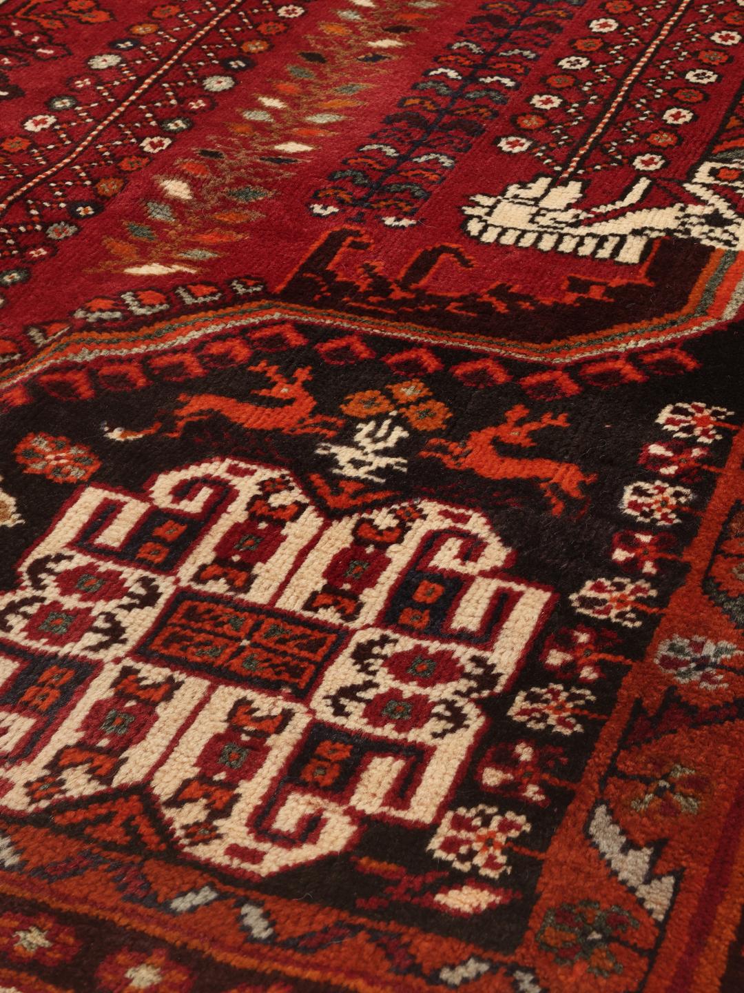 Hand-knotted Qashqai rug with traditional tribal patterns in red and dark tones