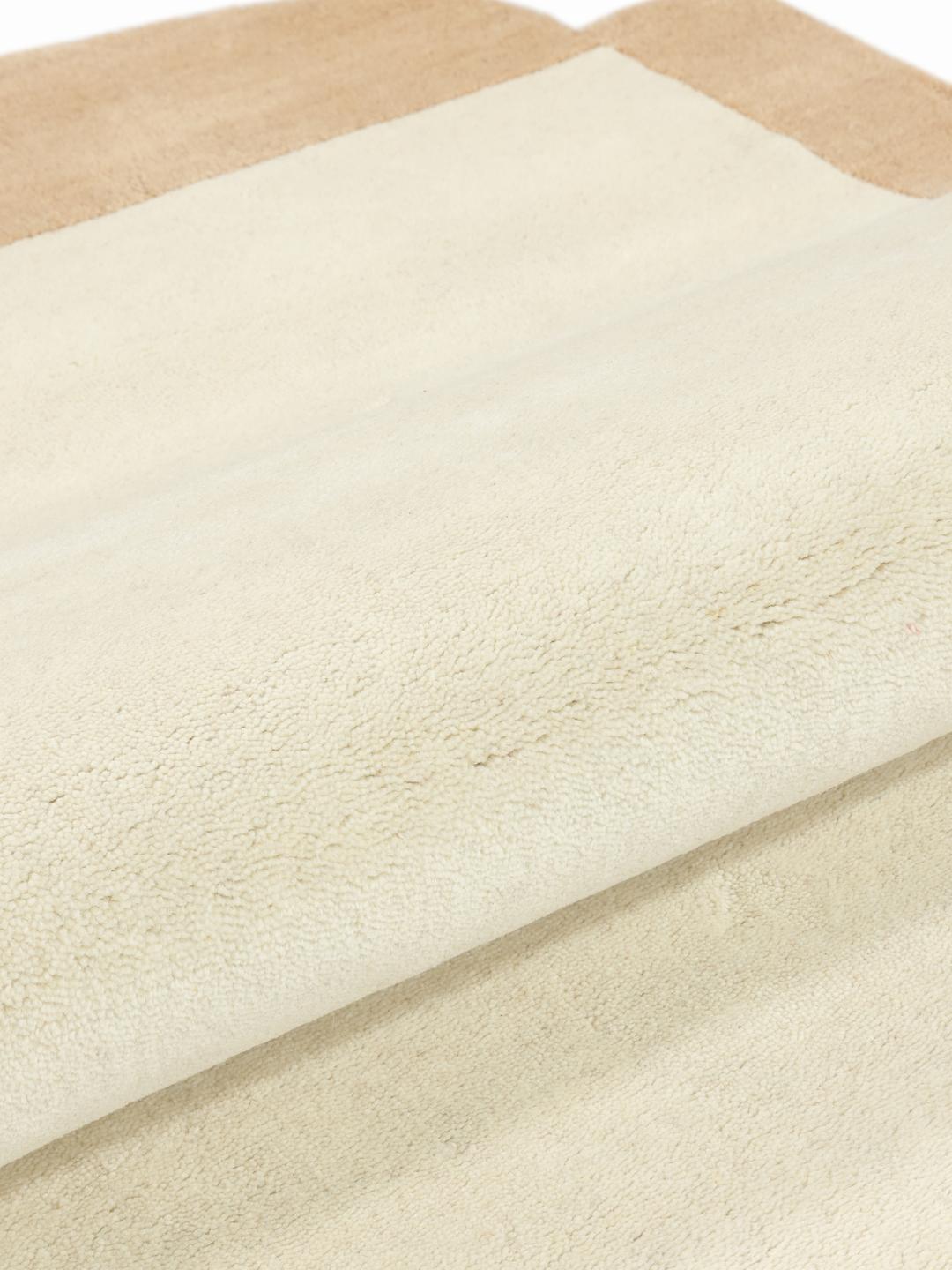 Een rechthoekig kleed in beige en off-white met een strakke moderne esthetiek.