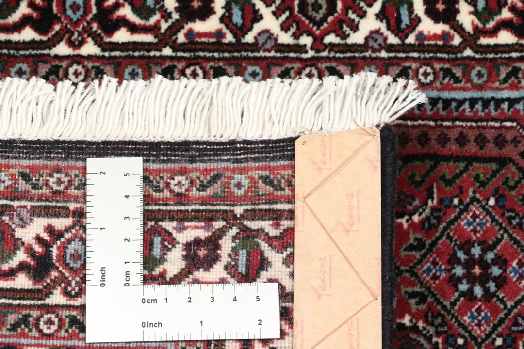 Een handgeknoopt Bidjar-tapijt uit het Midden-Oosten in donkerrood met complexe patronen.