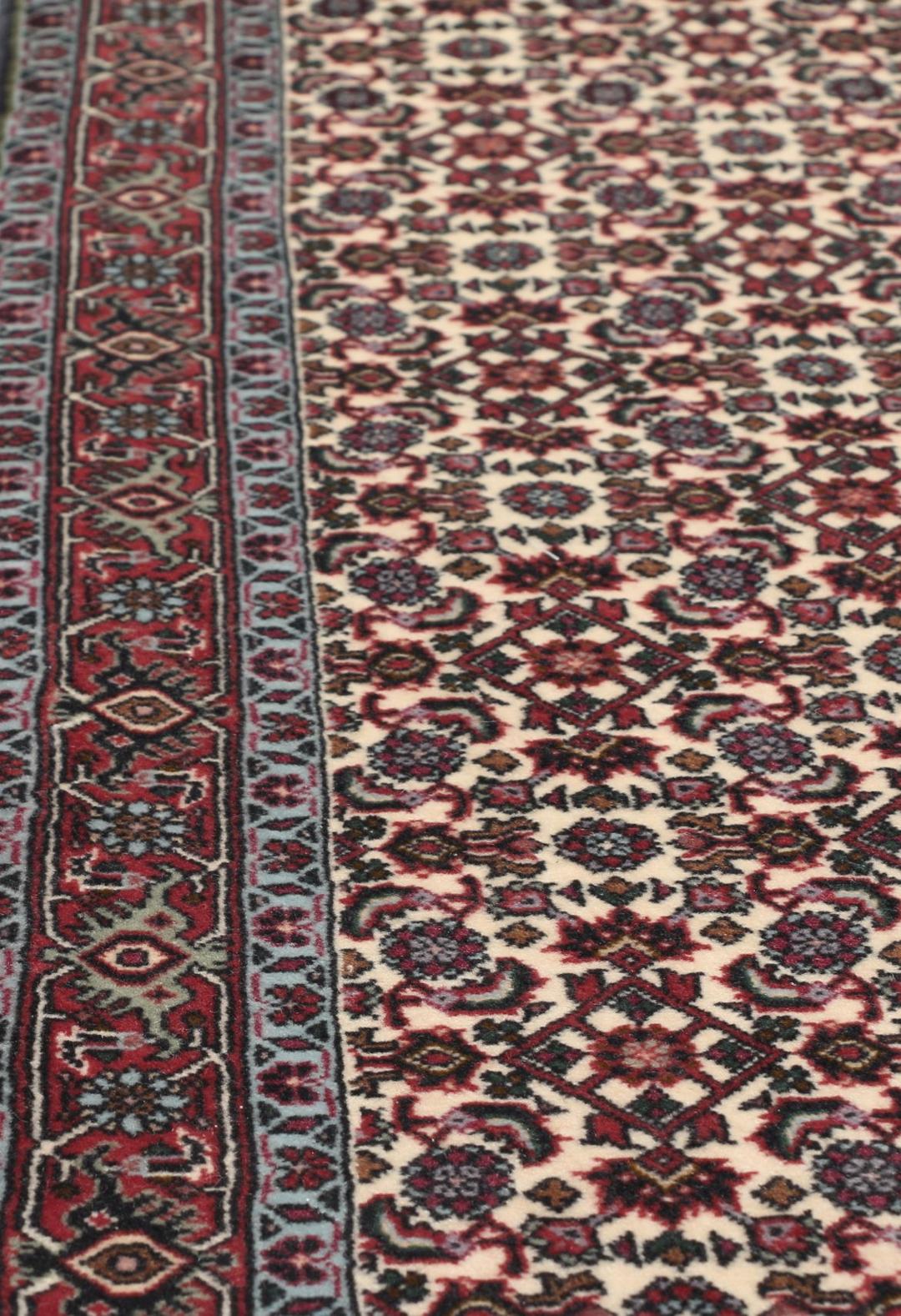 Een handgeknoopt Bidjar-tapijt uit het Midden-Oosten met een donkerrood en beige bloemenpatroon.