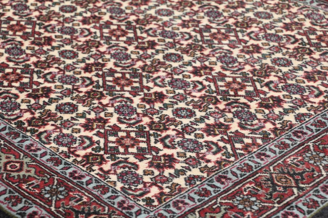 Een handgeknoopt Bidjar-tapijt uit het Midden-Oosten met een donkerrood en beige bloemenpatroon.