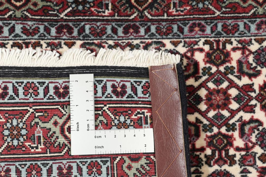 Een handgeknoopt Bidjar-tapijt uit het Midden-Oosten met een donkerrood en beige bloemenpatroon.