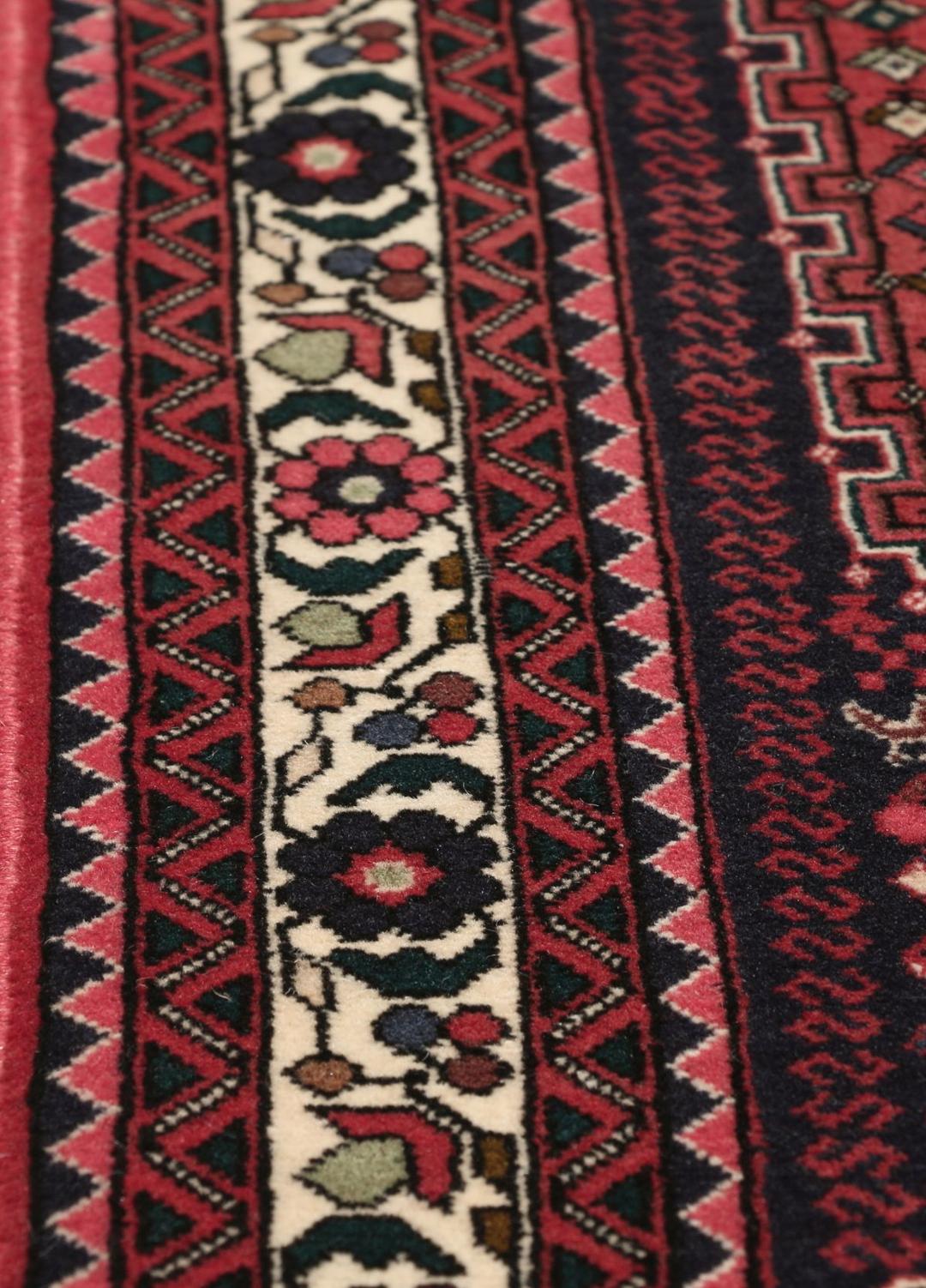 Et håndknyttet Abadeh-tæppe med en mørkerød bund og traditionelle geometriske motiver.