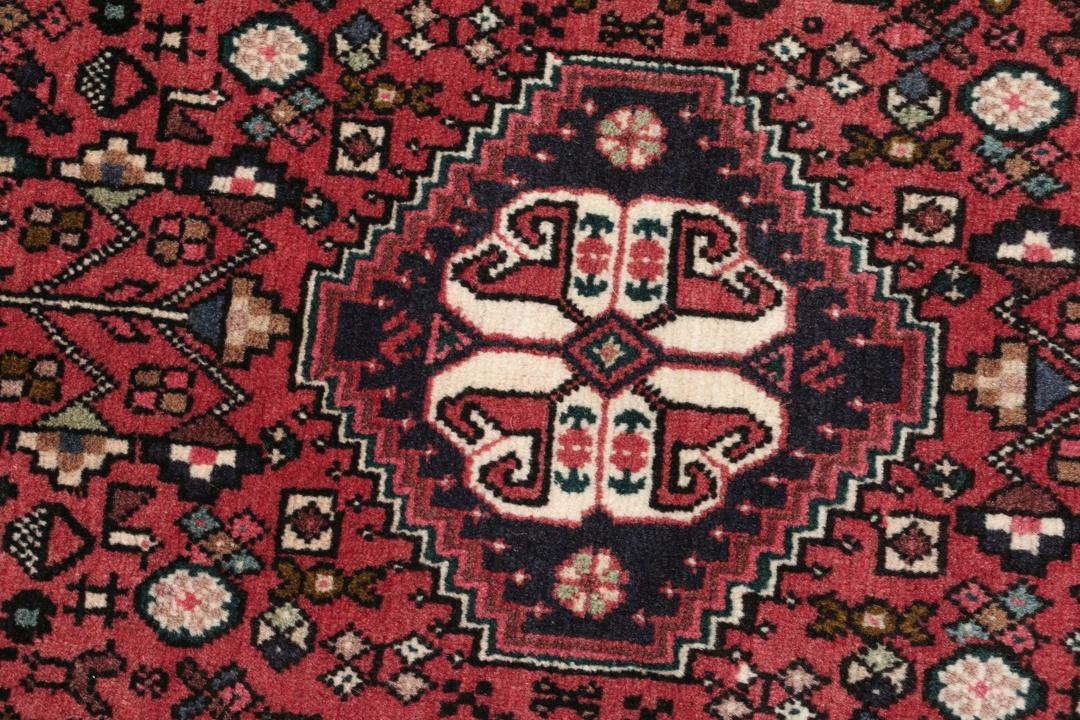 Et håndknyttet Abadeh-tæppe med en mørkerød bund og traditionelle geometriske motiver.