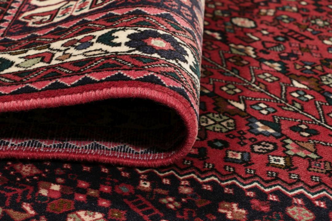 Et håndknyttet Abadeh-tæppe med en mørkerød bund og traditionelle geometriske motiver.