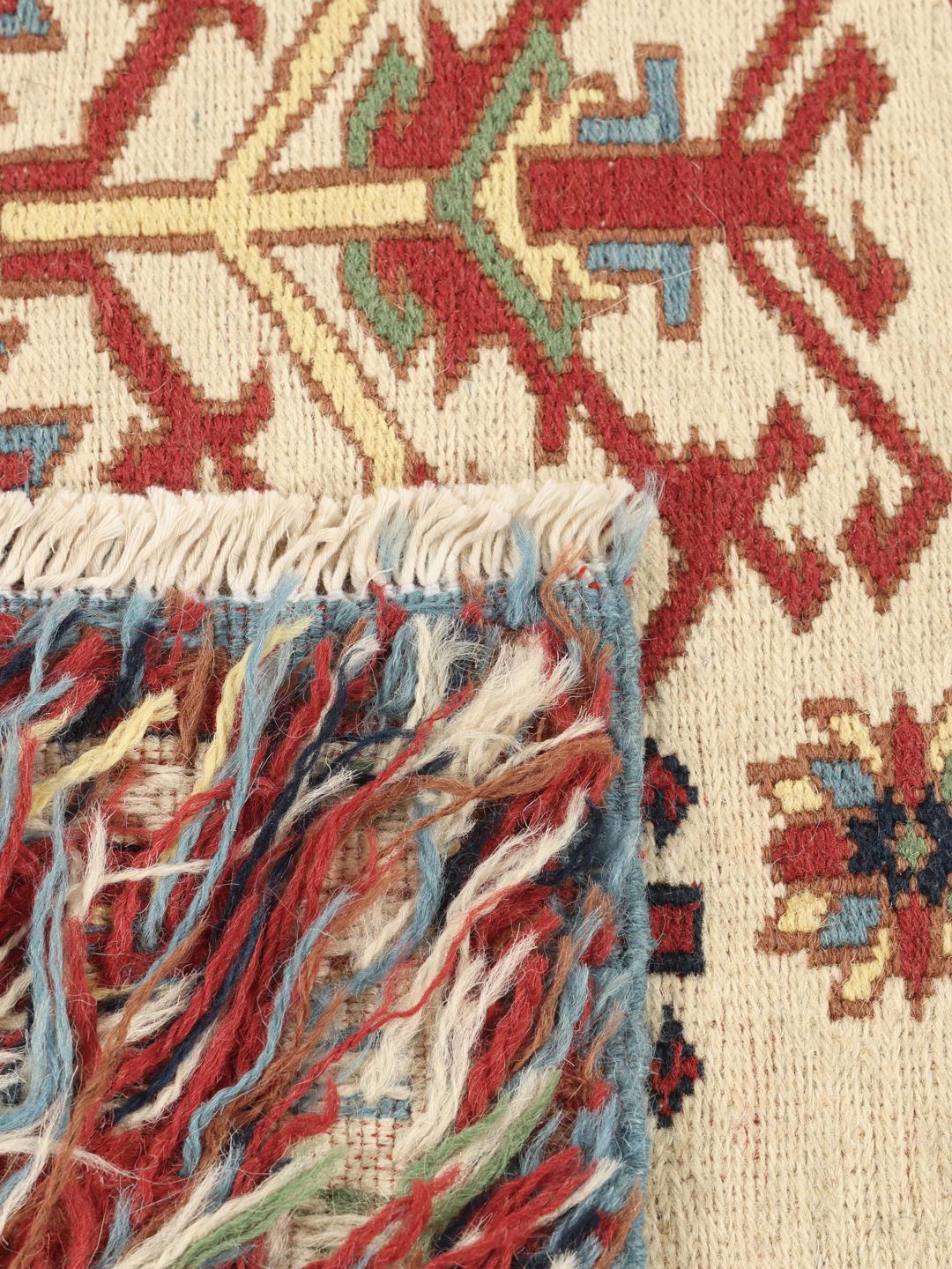Håndvævet afghansk Kelim-tæppe med blåt felt og ornamenterede geometriske motiver.