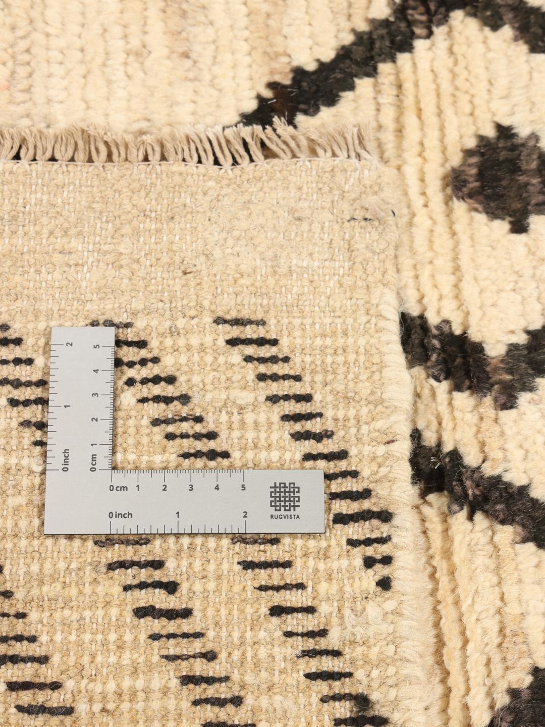 Håndknyttet tæppe fra Mellemøsten med sorte geometriske mønstre på en beige uldbaggrund