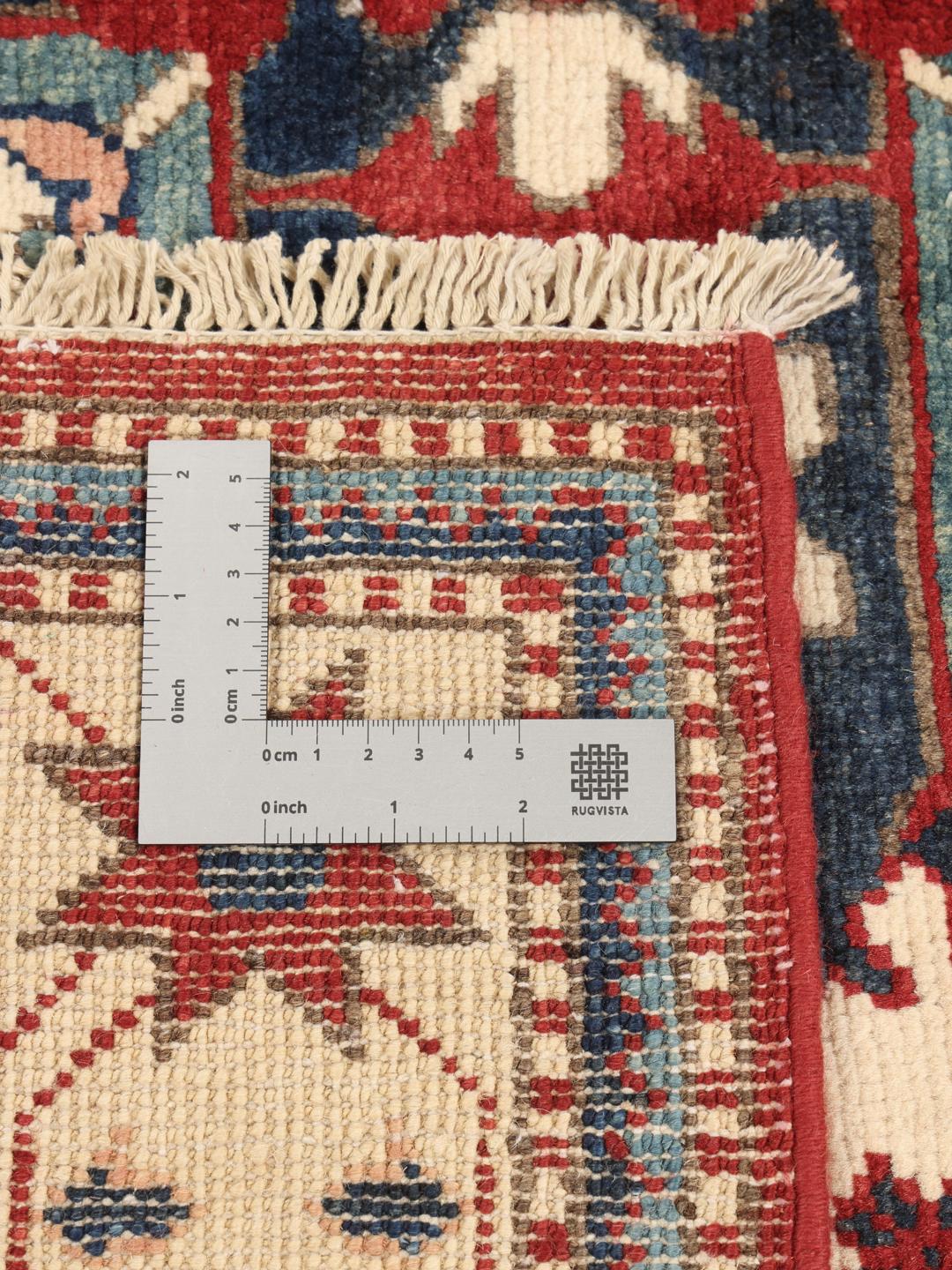 Tapis Kazak noué à la main en provenance d'Afghanistan avec un champ rouge et des motifs géométriques audacieux