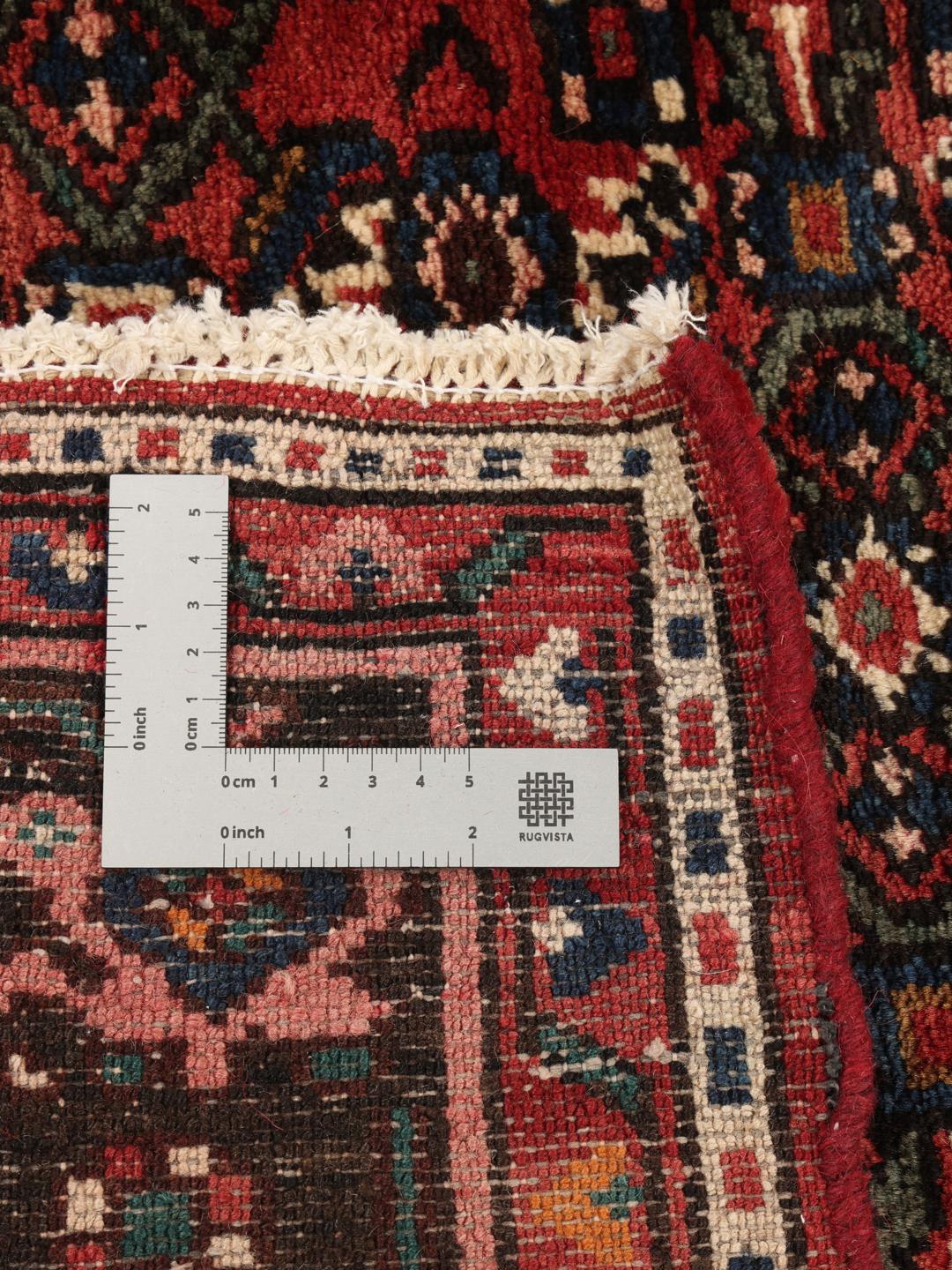 Et håndknyttet Hosseinabad-tæppe fra Mellemøsten med en rød flade og geometriske motiver.