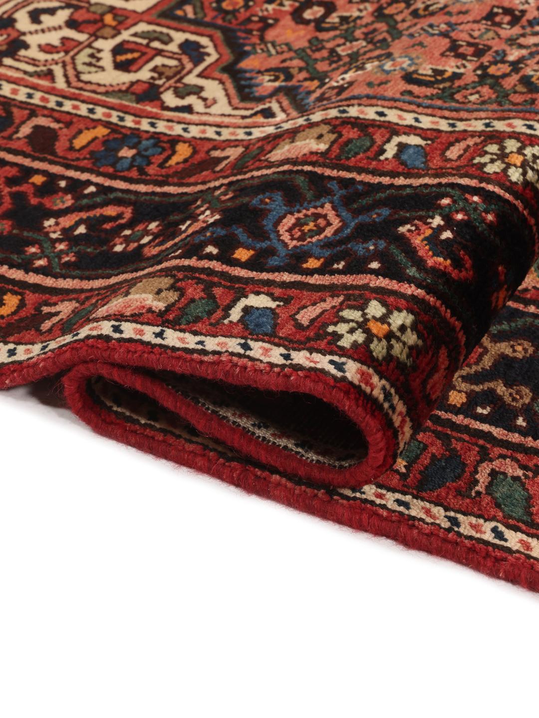 A hand-knotted Hosseinabad rug from the Middle East featuring a dark-red field and intricate patterns.