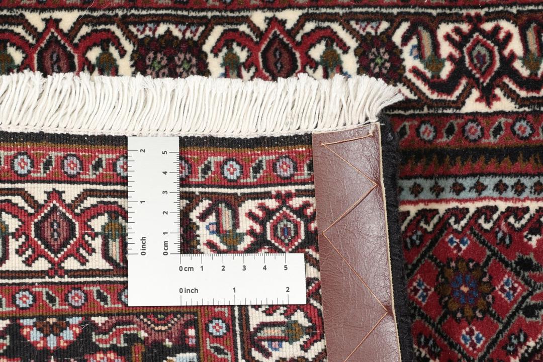 Een handgeknoopt Bidjar tapijt uit het Midden-Oosten in donkerrode en crèmekleurige tinten.