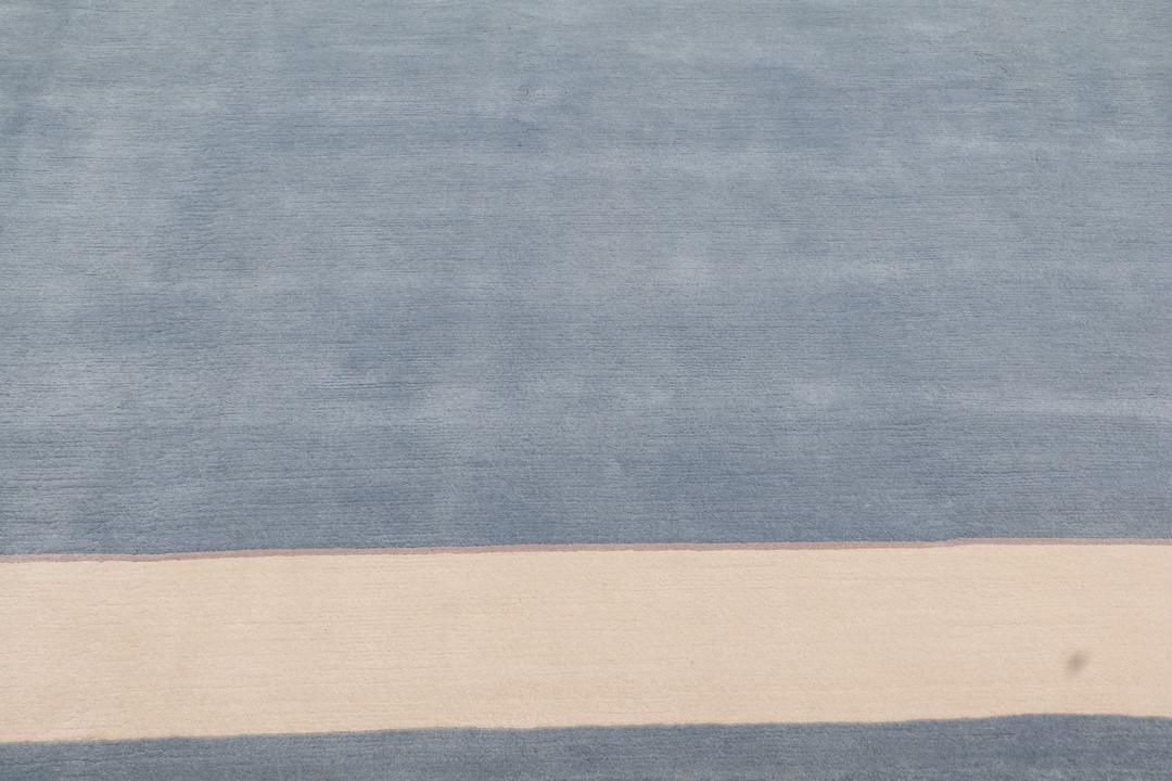 Handgeknoopt blauw wollen tapijt uit Nepal met een minimalistisch randontwerp