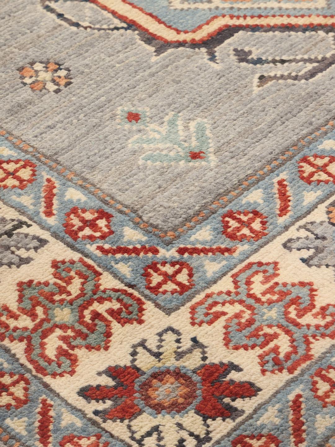 Handgeknoopt Kazak-tapijt uit Afghanistan met een grijs veld en traditionele geometrische motieven.