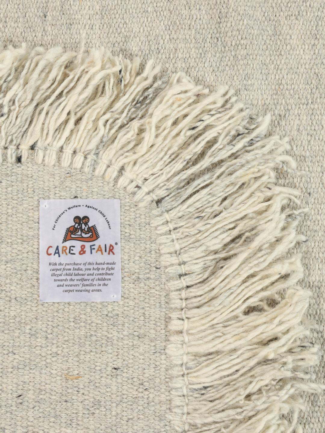Un tapis rond tissé gris avec des bords à franges.