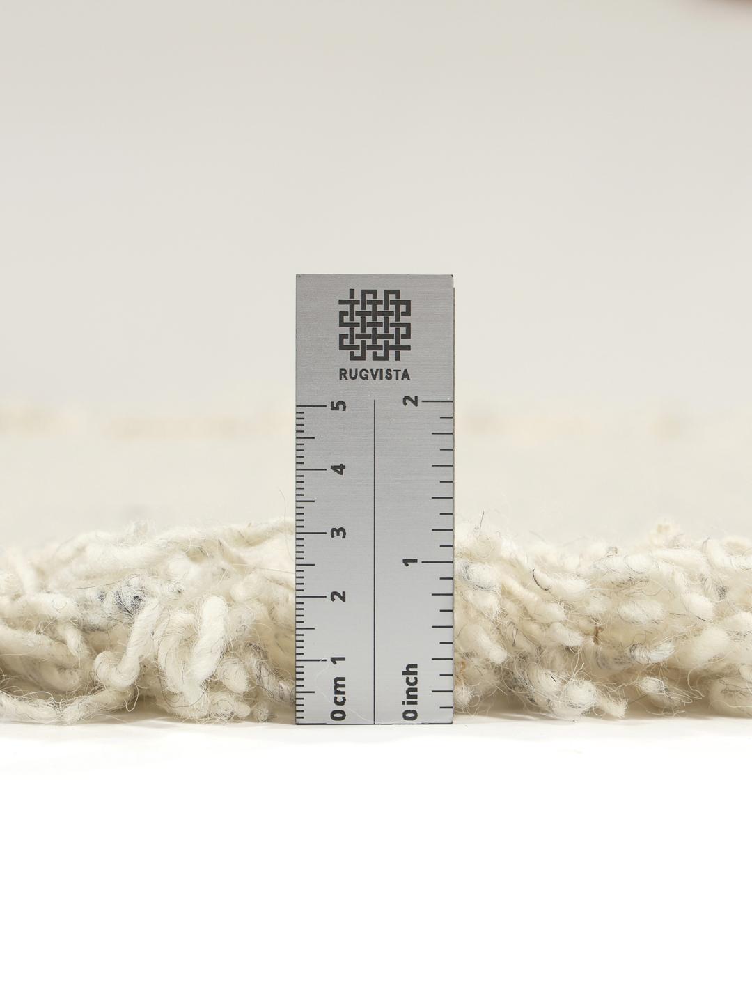 Un tapis gris tissé à la main avec des franges décoratives.