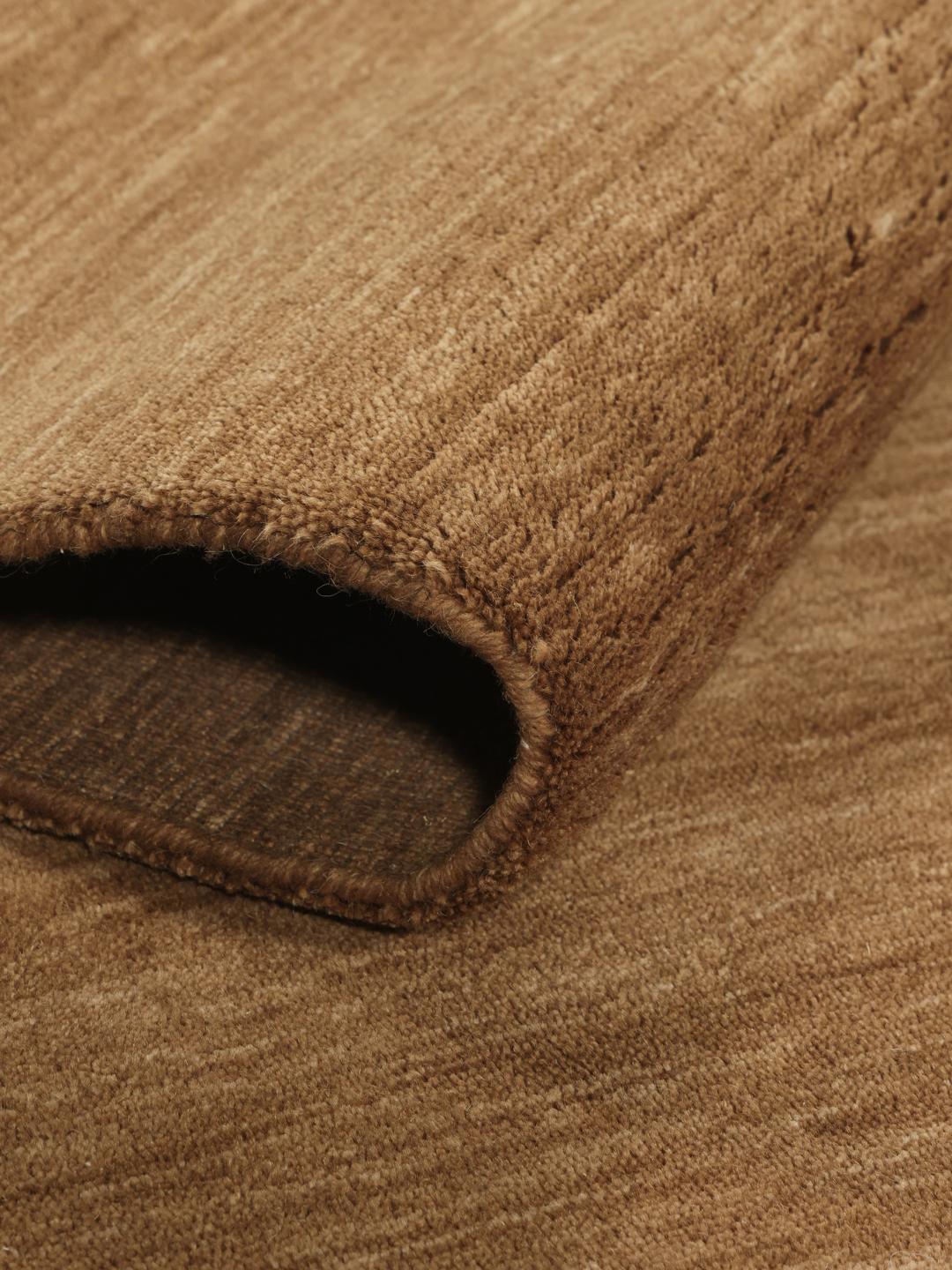 Un tapis à poils ras de couleur brune unie avec des franges courtes