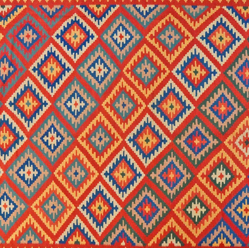 Et levende, håndvævet Kilim Qashqai-tæppe fra Mellemøsten med et dristigt rødt, blåt og gult geometrisk mønster.