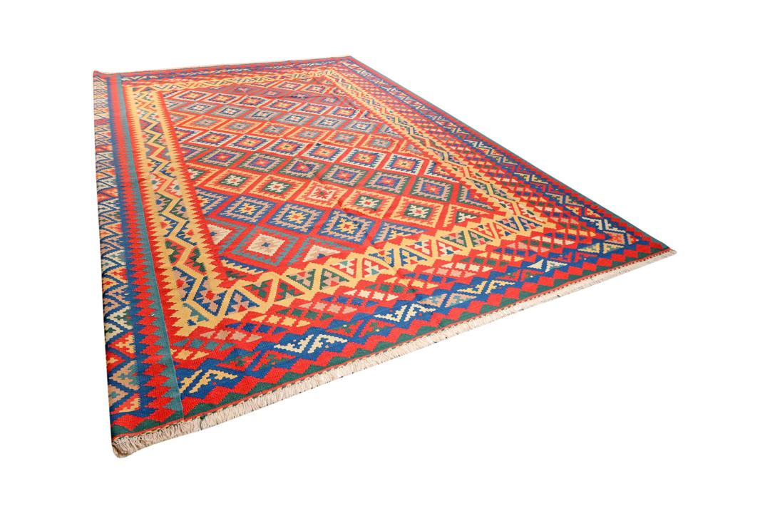 Et levende, håndvævet Kilim Qashqai-tæppe fra Mellemøsten med et dristigt rødt, blåt og gult geometrisk mønster.