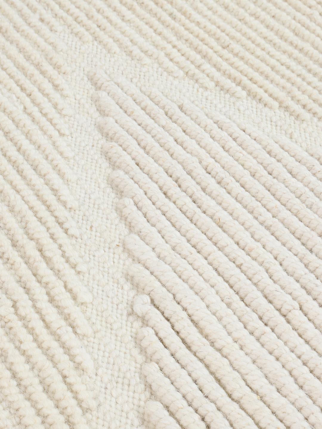Een handgeweven wit tapijt van Wool met een subtiel chevronpatroon en franjes.