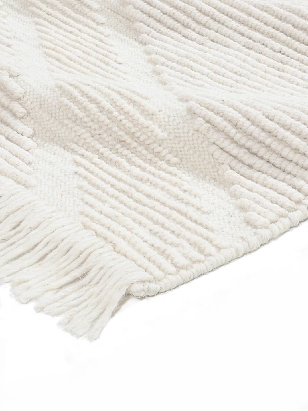Een handgeweven wit tapijt van Wool met een subtiel chevronpatroon en franjes.