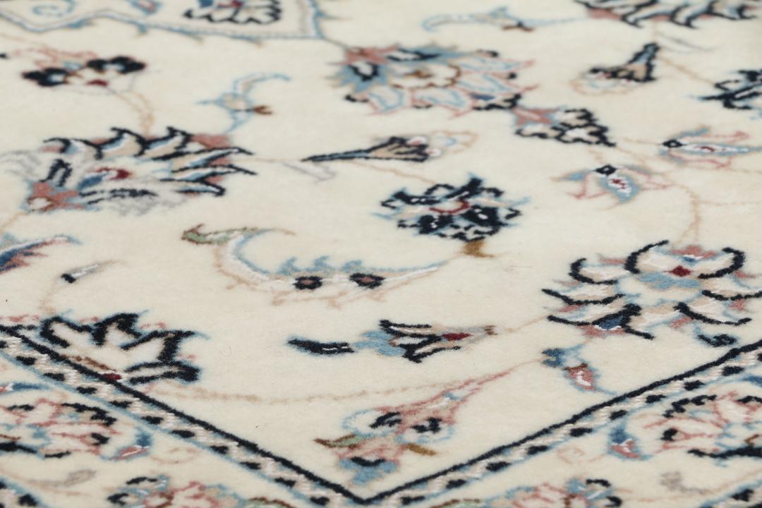 Een handgeknoopt Nain 9La-tapijt uit het Midden-Oosten met een beige achtergrond en bloemmotieven.