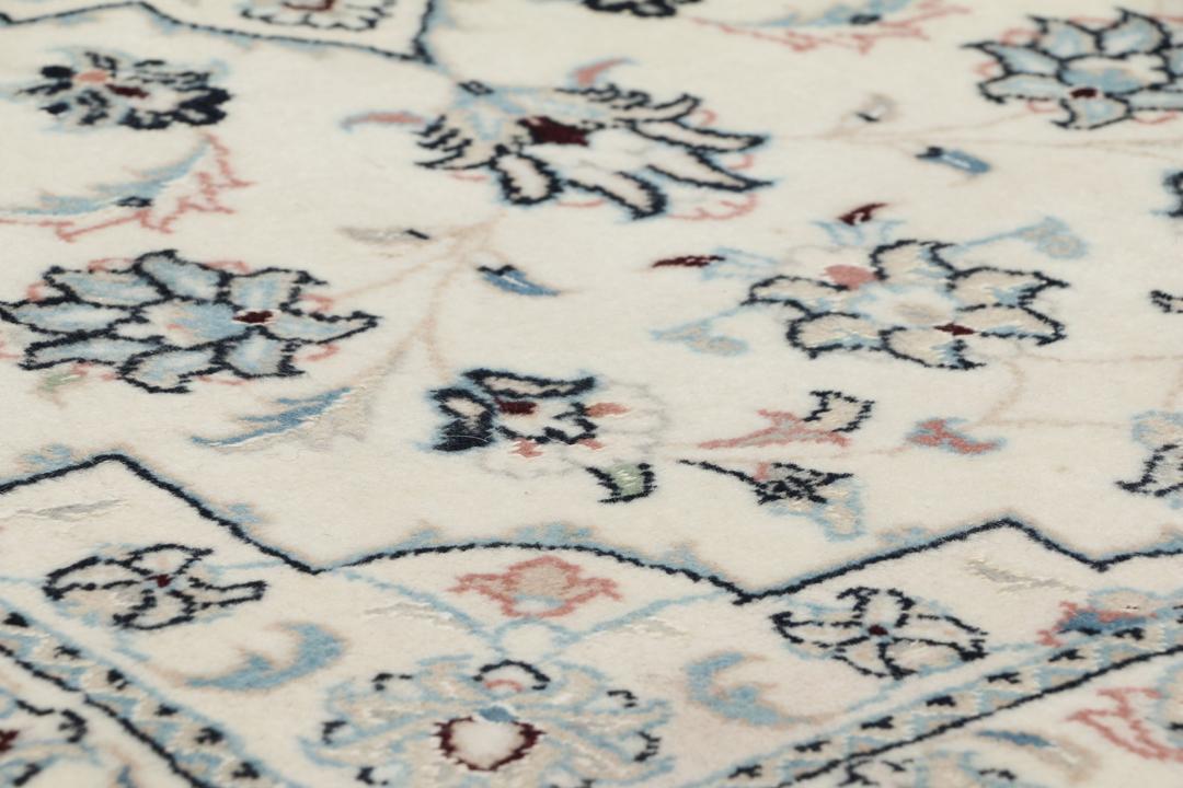 Een handgeknoopt Nain 9La tapijt met delicate bloemmotieven op een beige achtergrond.