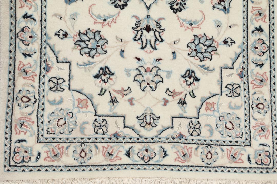 Een handgeknoopt Nain 9La tapijt met delicate bloemmotieven op een beige achtergrond.