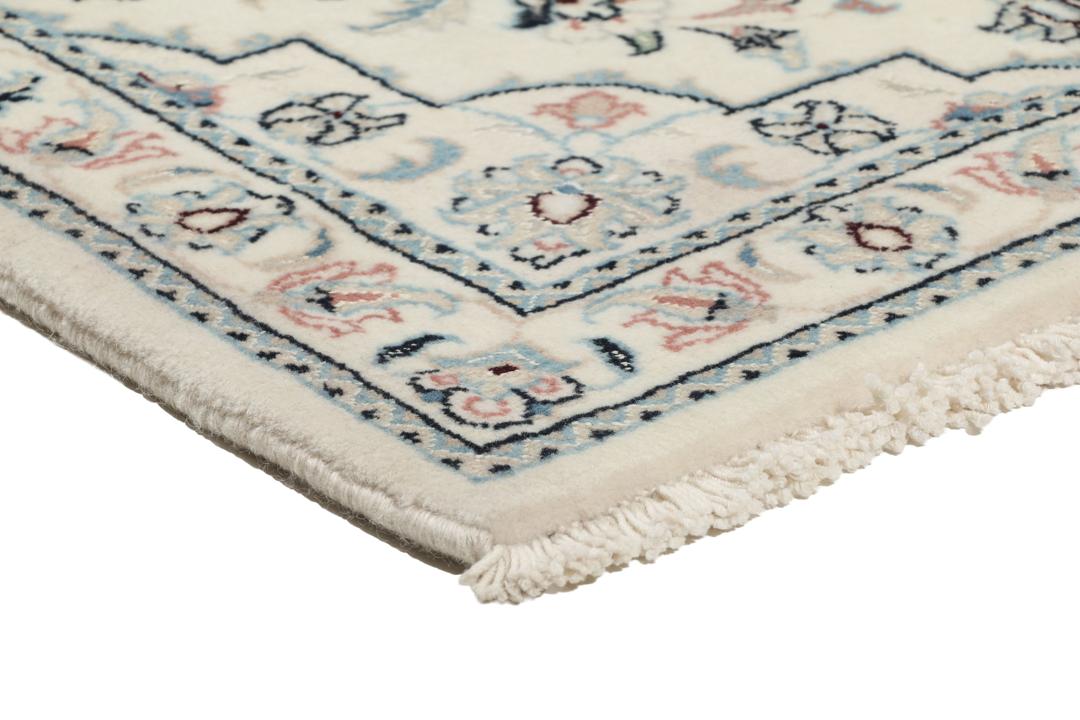 Een handgeknoopt Nain 9La tapijt met delicate bloemmotieven op een beige achtergrond.