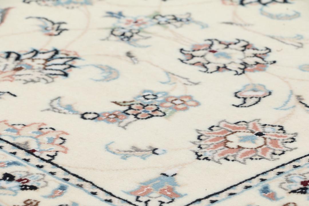 A hand-knotted Nain 9La rug from the Middle East featuring floral patterns in beige and soft blue.