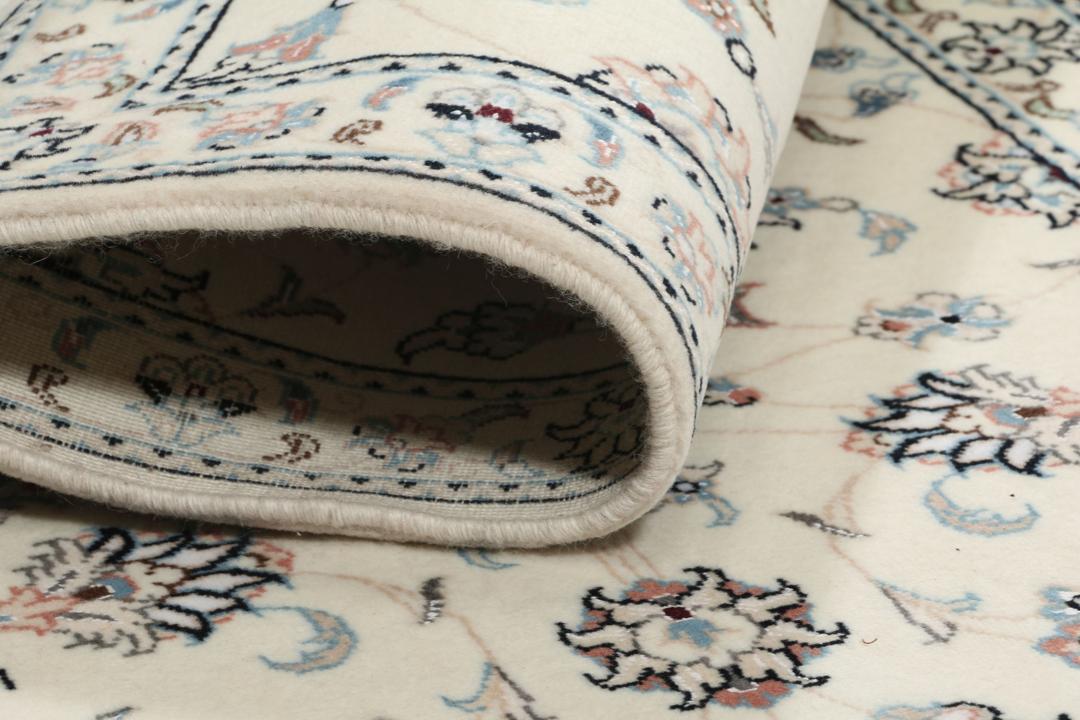 A hand-knotted Nain 9La rug from the Middle East featuring floral patterns in beige and soft blue.
