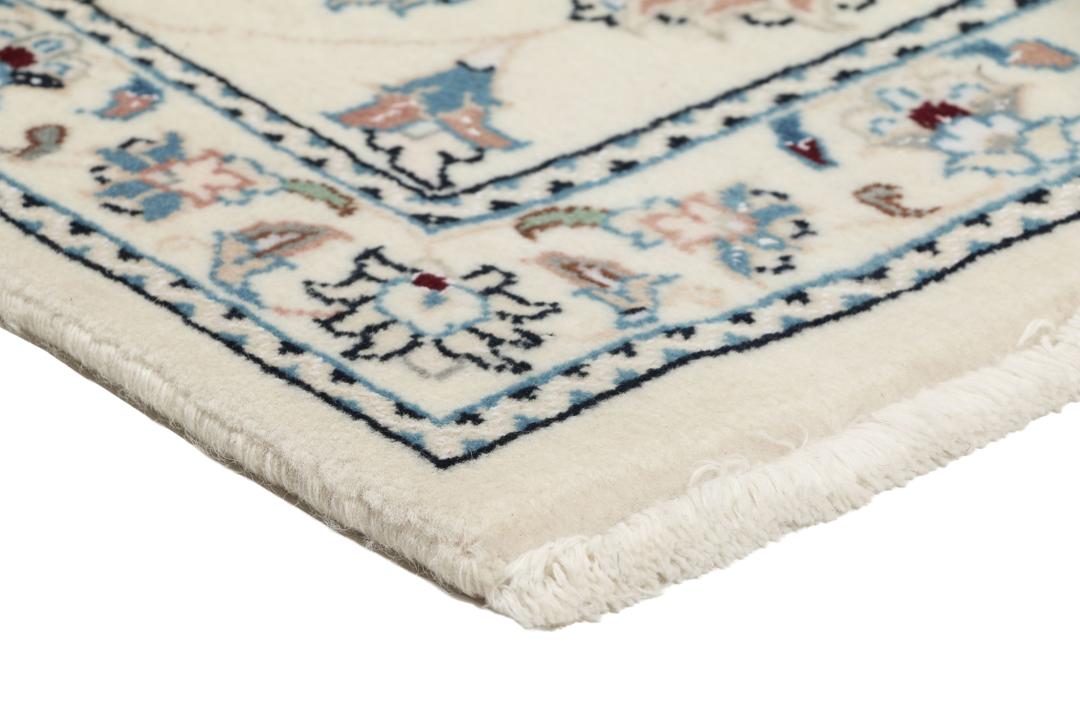 Een rechthoekig handgeknoopt Nain 9La tapijt uit het Midden-Oosten met een beige achtergrond en bloempatronen in blauw en roze.