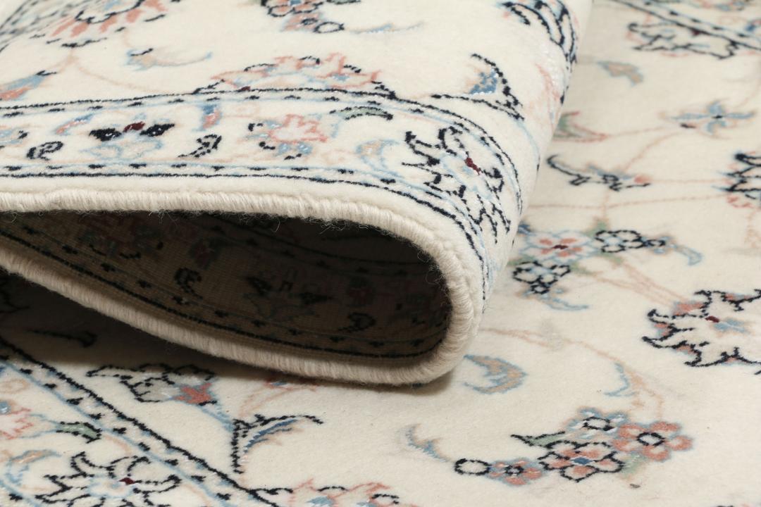 Een rechthoekig handgeknoopt Nain 9La tapijt uit het Midden-Oosten met een beige achtergrond en bloempatronen in blauw en roze.