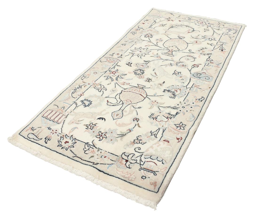 Et rektangulært håndknyttet Nain 9La-tæppe med delikate blomstermotiver i beige og blå nuancer.