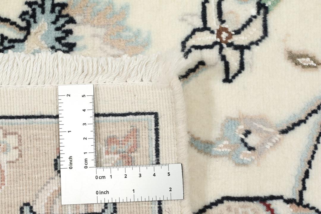 Et rektangulært håndknyttet Nain 9La-tæppe med delikate blomstermotiver i beige og blå nuancer.