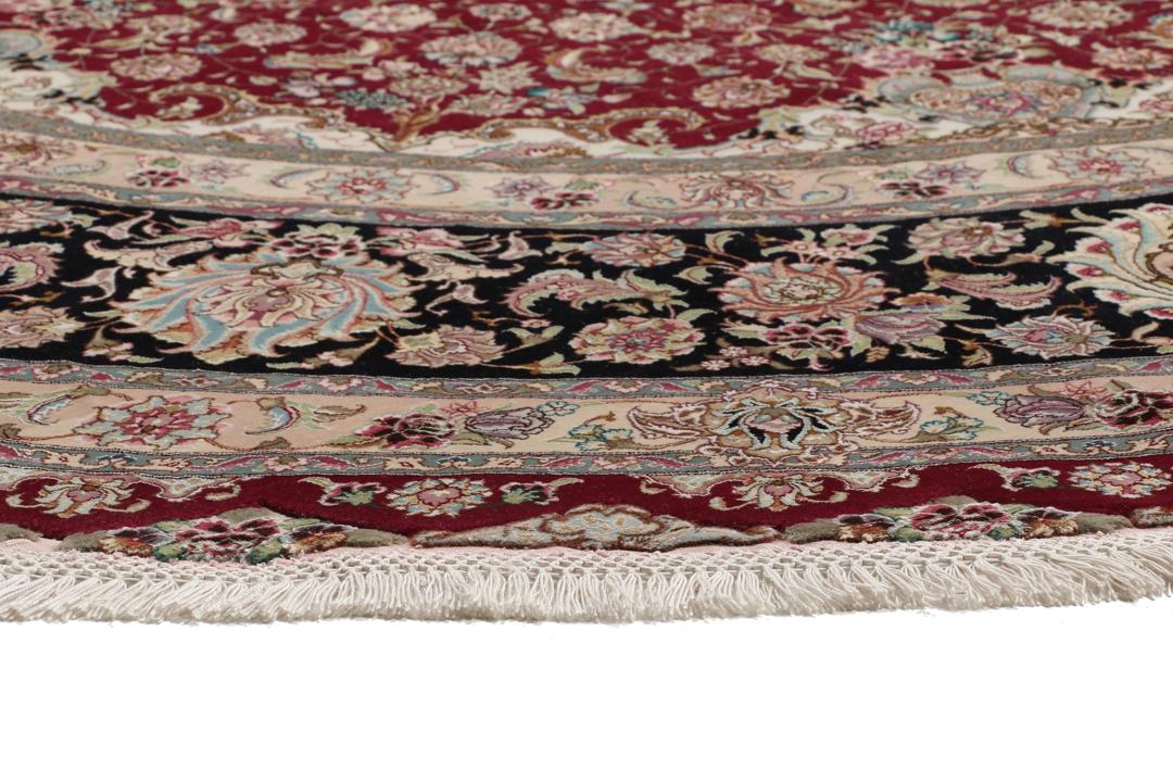 Een rond, handgeknoopt Tabriz-tapijt uit het Midden-Oosten met een levendig rood en zwart bloemendesign.