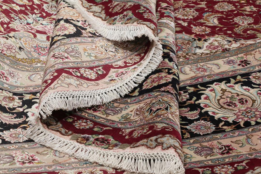 Een rond, handgeknoopt Tabriz-tapijt uit het Midden-Oosten met een levendig rood en zwart bloemendesign.