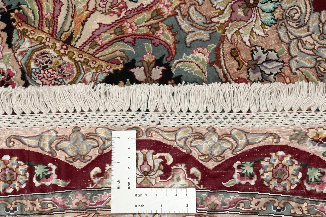 Een rond, handgeknoopt Tabriz-tapijt uit het Midden-Oosten met een levendig rood en zwart bloemendesign.