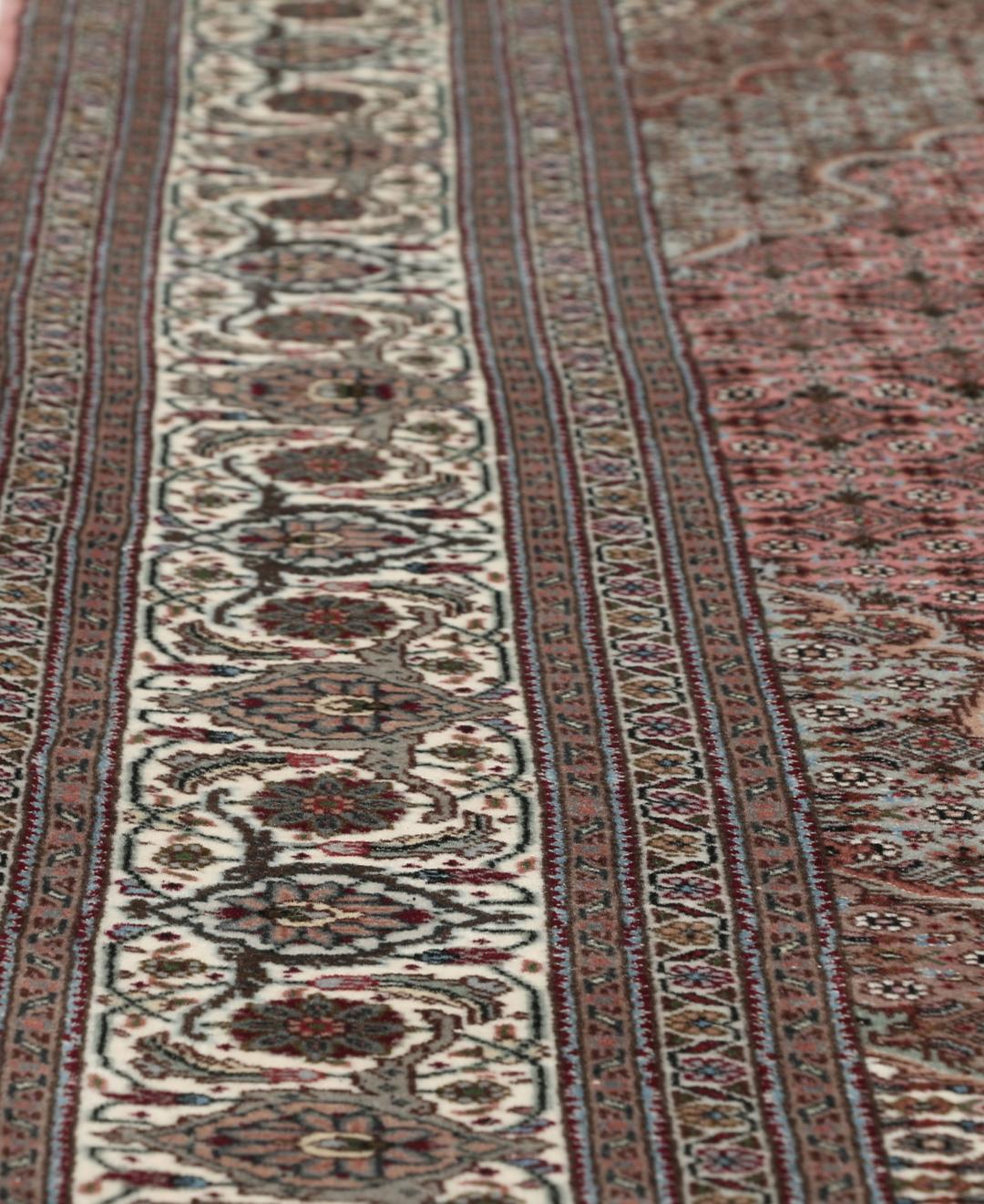 Et rektangulært håndknyttet Tabriz-tæppe fra Mellemøsten i mørkerøde og mørkeblå toner.