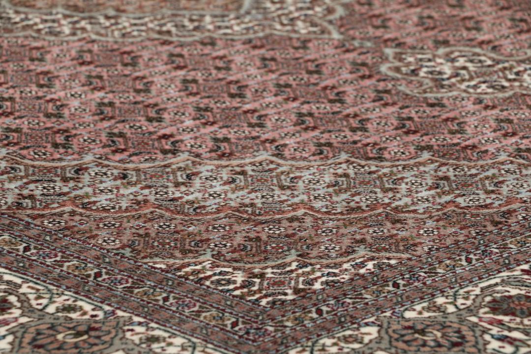 Et rektangulært håndknyttet Tabriz-tæppe fra Mellemøsten i mørkerøde og mørkeblå toner.