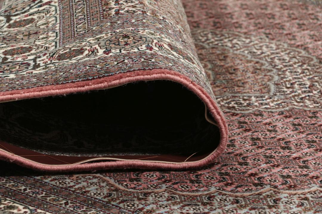 Et rektangulært håndknyttet Tabriz-tæppe fra Mellemøsten i mørkerøde og mørkeblå toner.