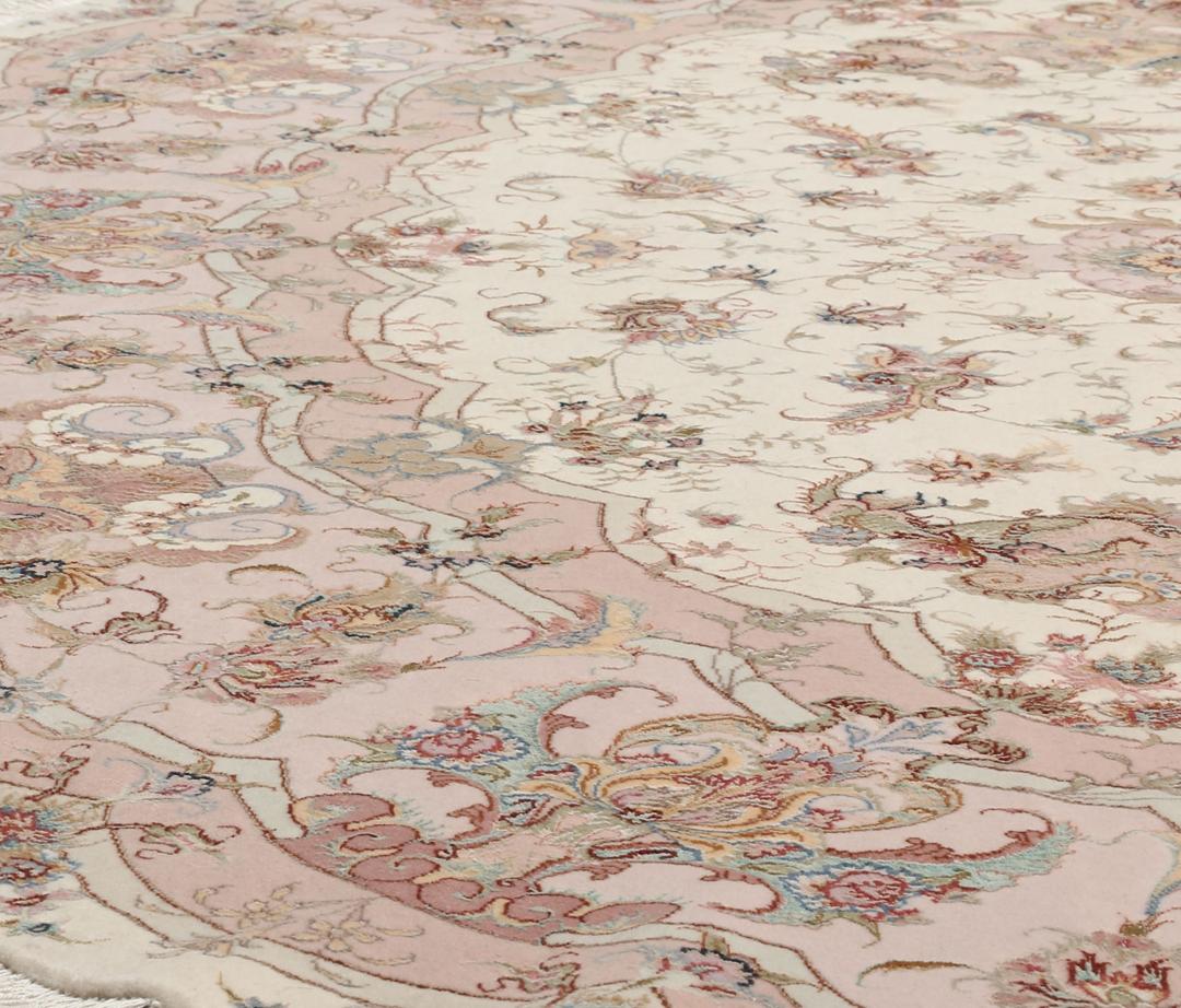 Rundt Tabriz-tæppe med indviklede blomstermønstre i rosa og creme fra Mellemøsten.