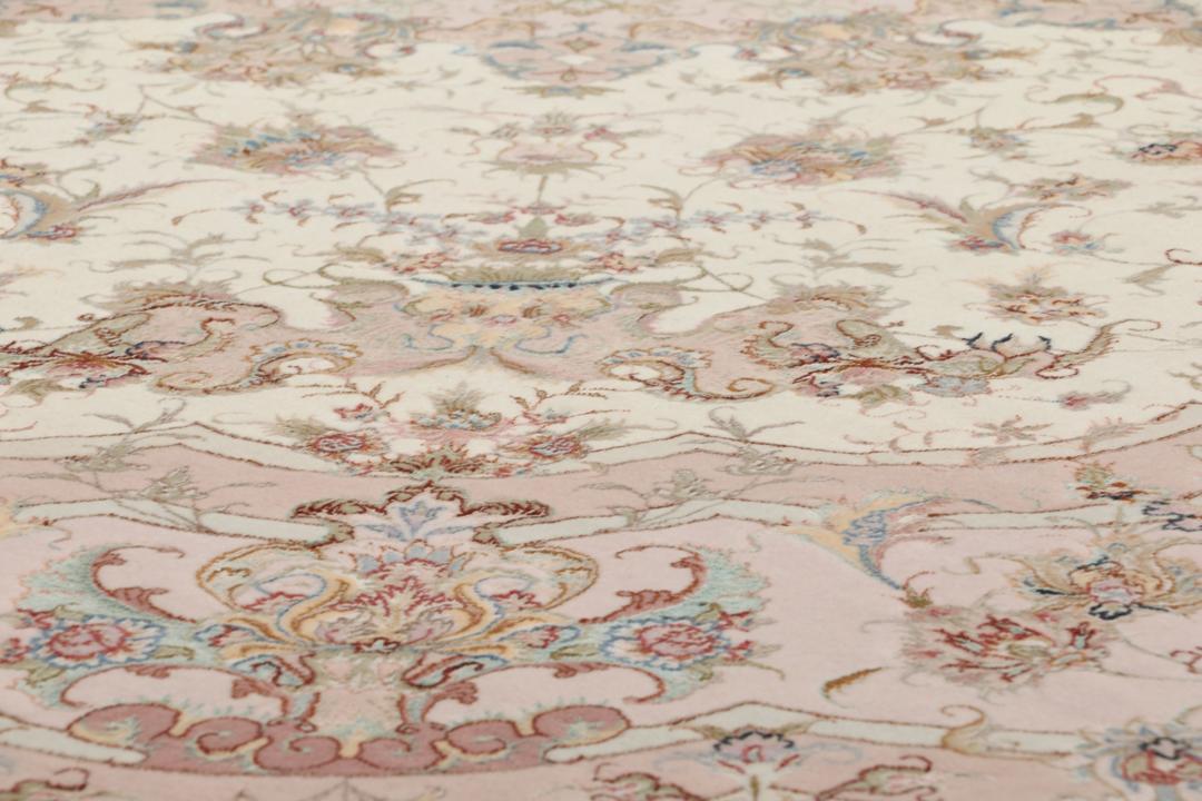 Rundt Tabriz-tæppe med indviklede blomstermønstre i rosa og creme fra Mellemøsten.