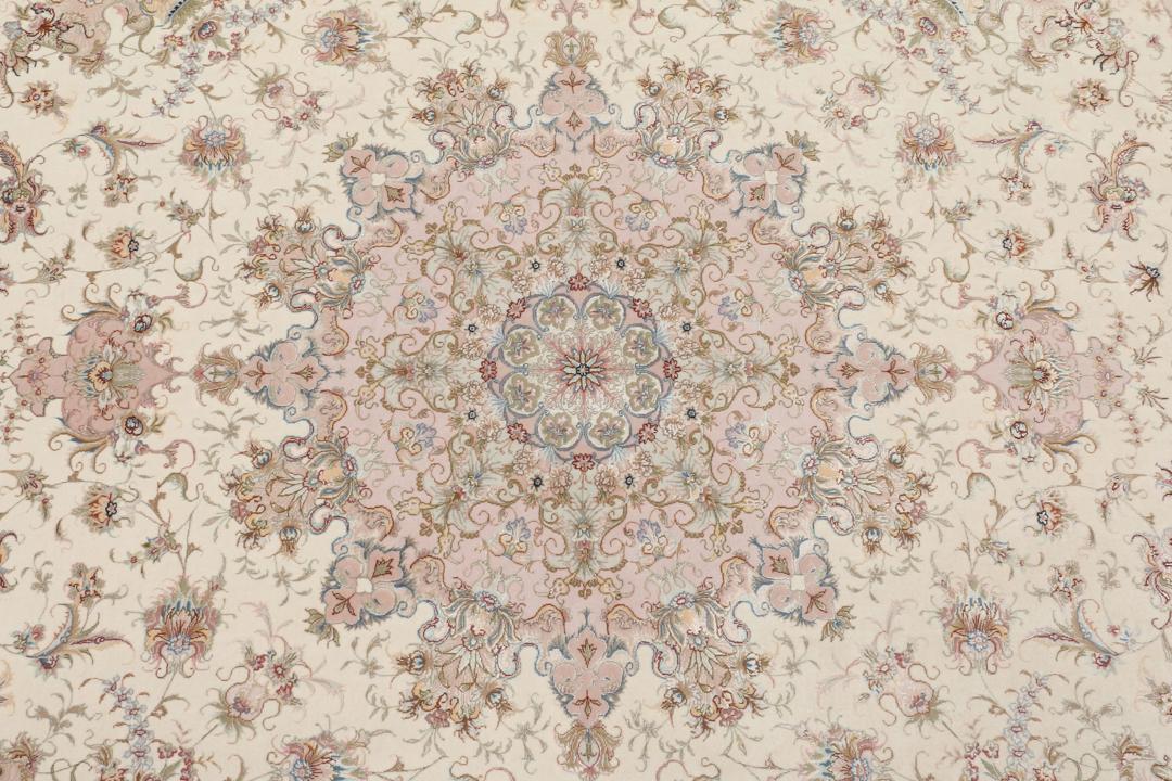 Rundt Tabriz-tæppe med indviklede blomstermønstre i rosa og creme fra Mellemøsten.