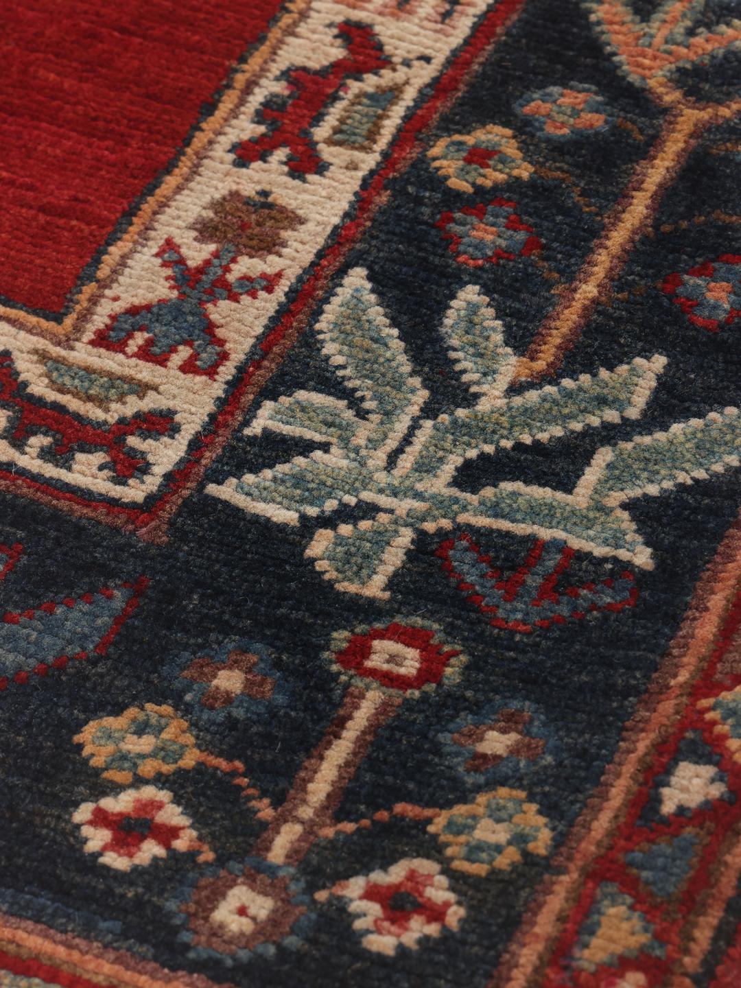Covor Kazak înnodat manual din Afganistan, cu un câmp roșu și medalioane florale albastre.