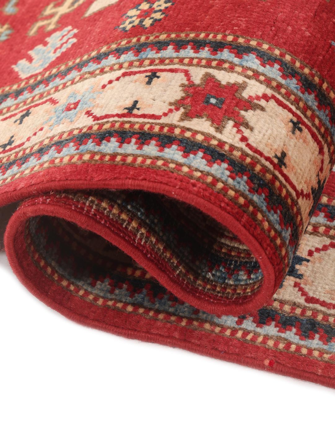 Een handgeknoopt Afghaans Kazak tapijt met gedurfde geometrische rode, blauwe en crèmekleurige motieven.